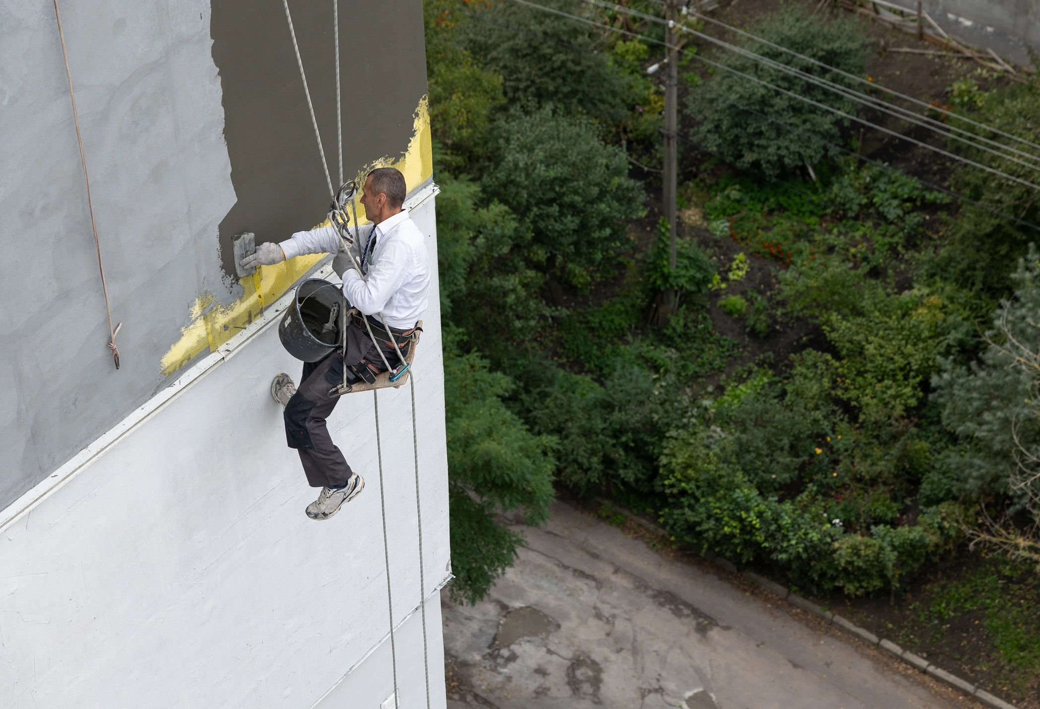 Construction worker performing exterior envelope work while secured with safety ropes